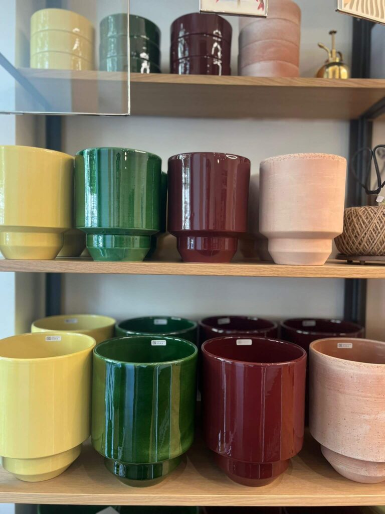 Bunte Keramiktöpfe auf Holzregalen im Geschäft.