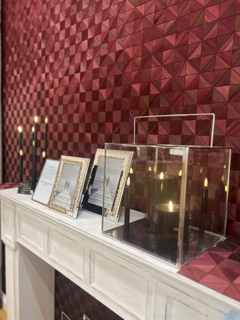 Dekorativer Kamin mit Kerzen und Bildern.