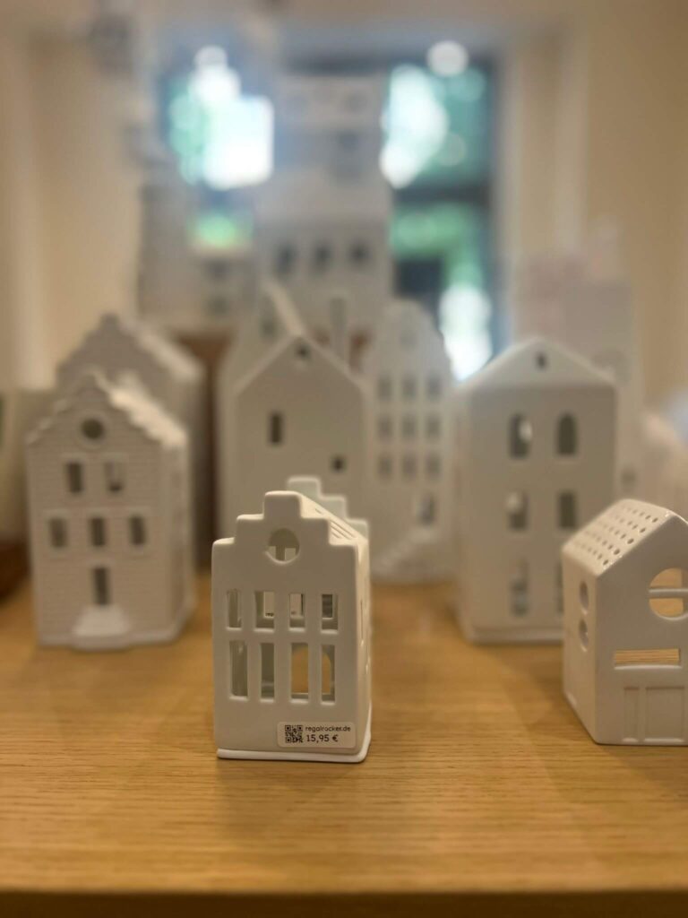 Keramik-Gebäude auf Holzregal ausgestellt.