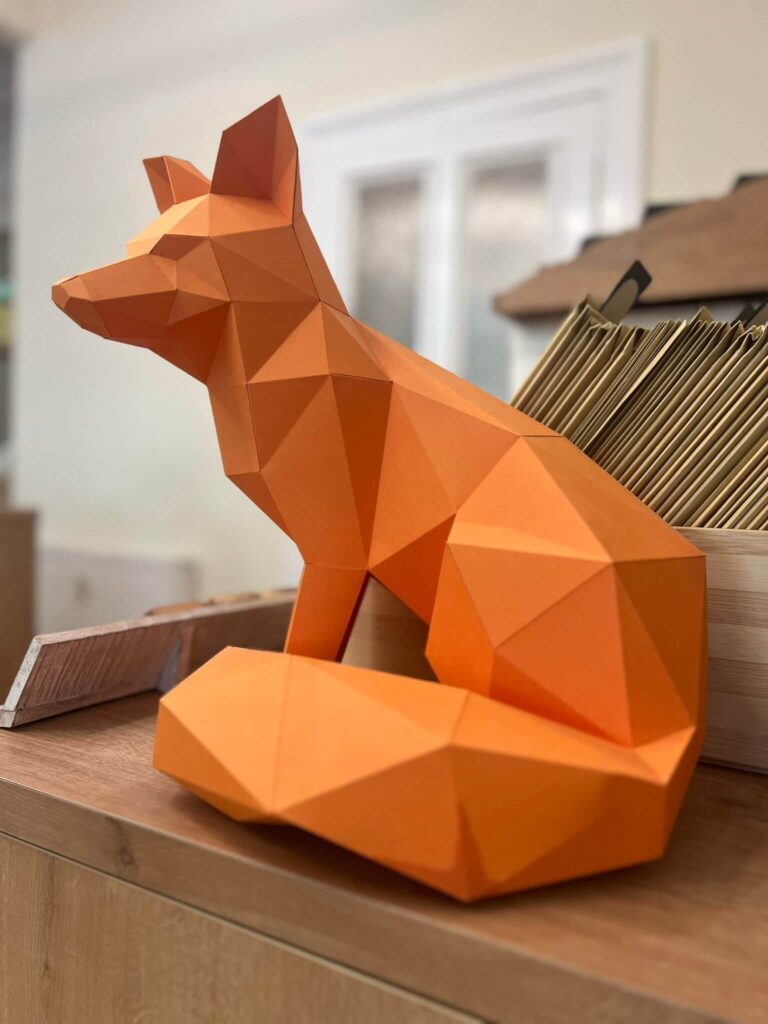 Origami-Fuchs aus orangefarbenem Papier auf Tisch