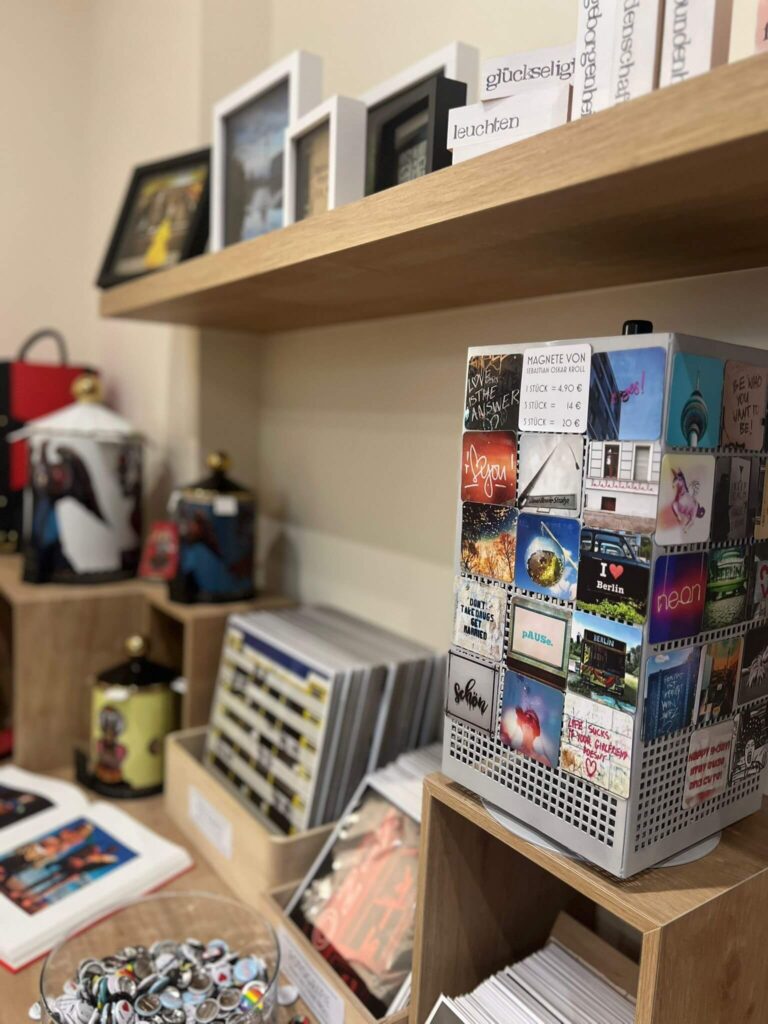 Verschiedene Postkarten und Magnete auf Regalen ausgestellt.